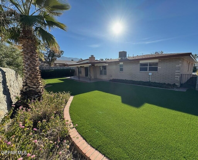 rear view of property featuring cooling unit, a yard, and a patio