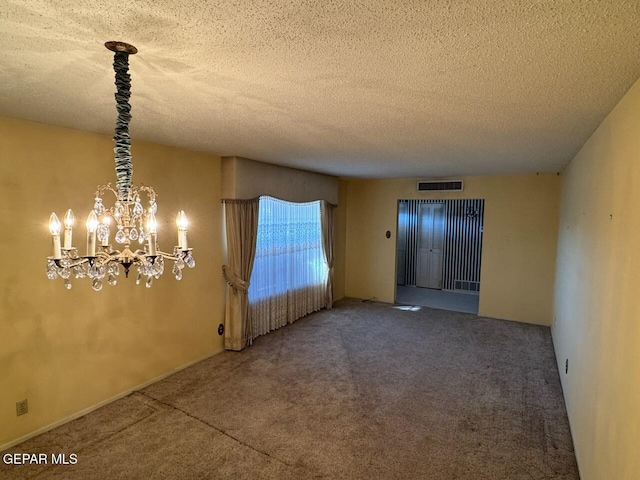 empty room featuring carpet, a textured ceiling, and an inviting chandelier