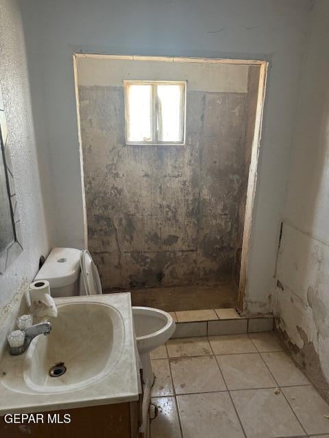 bathroom with toilet, walk in shower, vanity, and tile patterned flooring