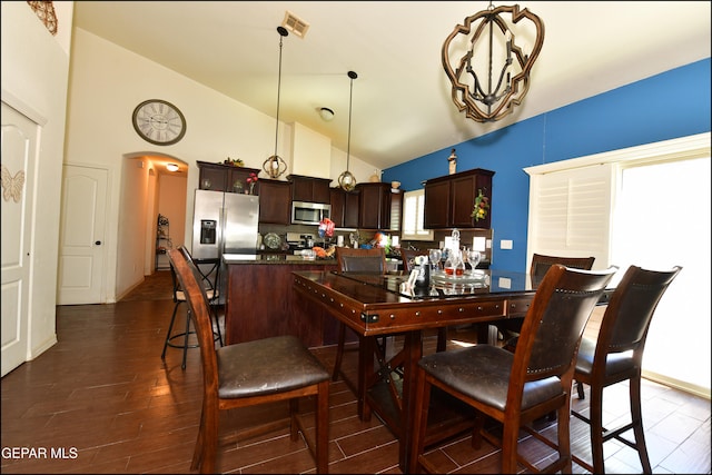 dining area featuring a chandelier, dark wood-type flooring, and high vaulted ceiling