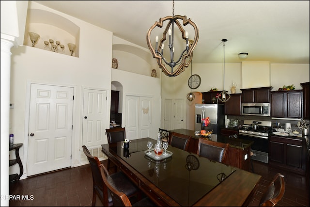 dining room featuring decorative columns, an inviting chandelier, dark wood-type flooring, and high vaulted ceiling