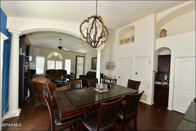 dining area featuring ceiling fan with notable chandelier, decorative columns, and dark wood-type flooring