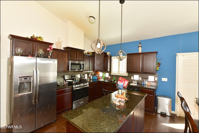 kitchen with dark hardwood / wood-style floors, vaulted ceiling, a kitchen island, appliances with stainless steel finishes, and decorative light fixtures