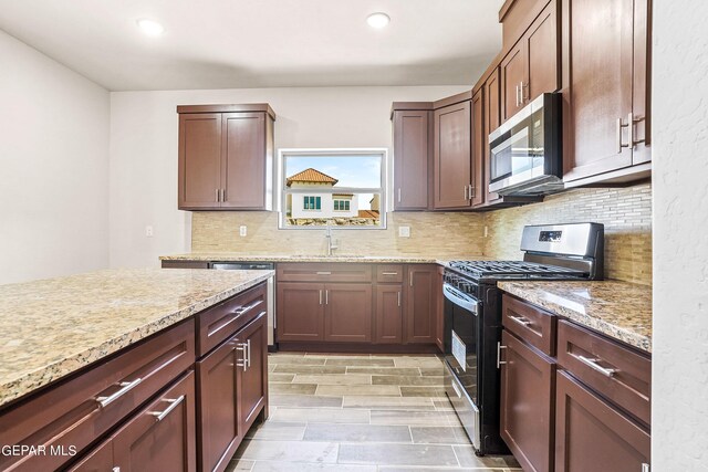 kitchen with sink, tasteful backsplash, light hardwood / wood-style flooring, appliances with stainless steel finishes, and light stone countertops