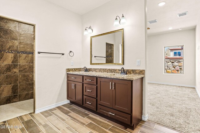 bathroom with a tile shower and vanity