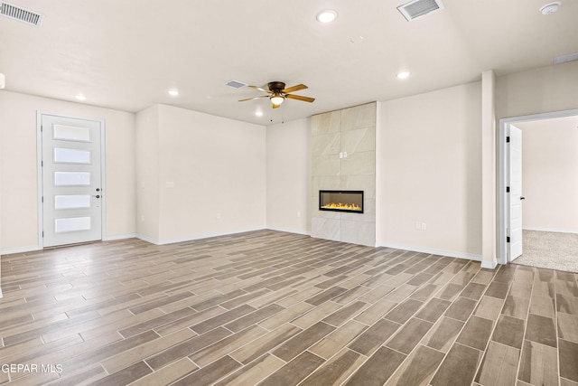 unfurnished living room featuring a tile fireplace, ceiling fan, and hardwood / wood-style flooring