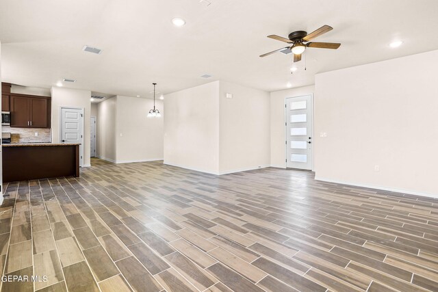 unfurnished living room with ceiling fan with notable chandelier and hardwood / wood-style floors