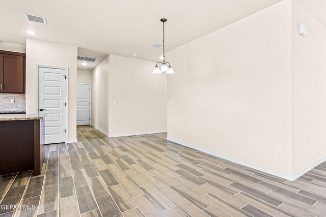 unfurnished dining area featuring a chandelier and hardwood / wood-style floors