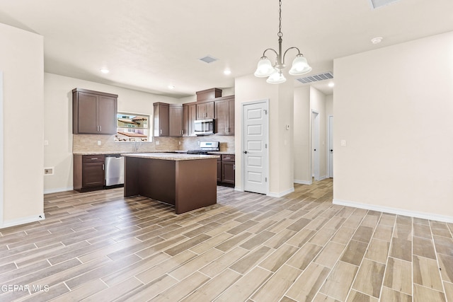 kitchen featuring a center island, light hardwood / wood-style flooring, an inviting chandelier, appliances with stainless steel finishes, and decorative light fixtures