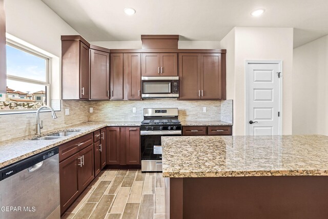 kitchen featuring light stone counters, sink, tasteful backsplash, light hardwood / wood-style flooring, and stainless steel appliances