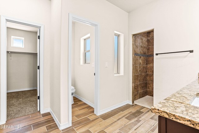 bathroom featuring tiled shower, vanity, and toilet