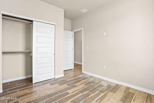 unfurnished bedroom featuring a closet and dark hardwood / wood-style floors