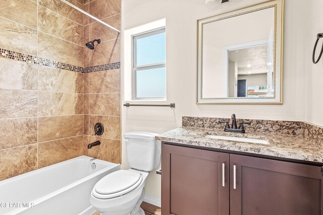 full bathroom with tiled shower / bath, vanity, and toilet