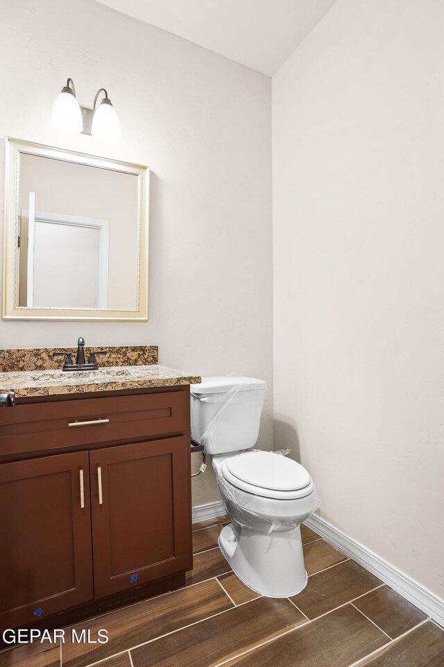 bathroom with vanity, toilet, and hardwood / wood-style flooring