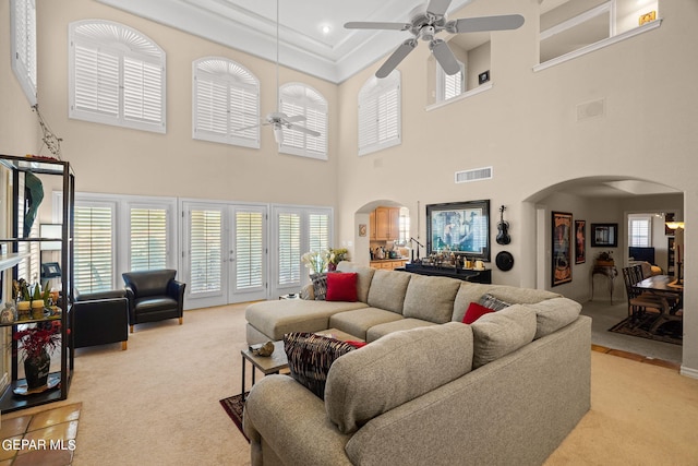 carpeted living room with a towering ceiling, ceiling fan, and french doors