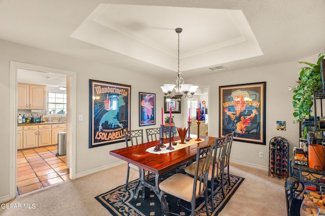 carpeted dining space with a raised ceiling and a chandelier