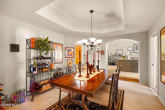 851 Via Alegre Ln, El Paso, TX 79912 - dining space featuring light carpet, arched walkways, a raised ceiling, and a chandelier