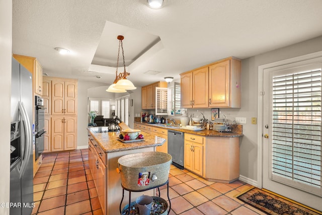 kitchen featuring hanging light fixtures, a kitchen island, a textured ceiling, appliances with stainless steel finishes, and light brown cabinetry