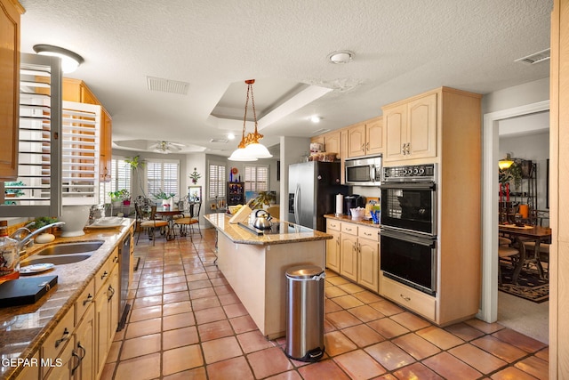 kitchen featuring pendant lighting, a textured ceiling, stainless steel appliances, and a center island