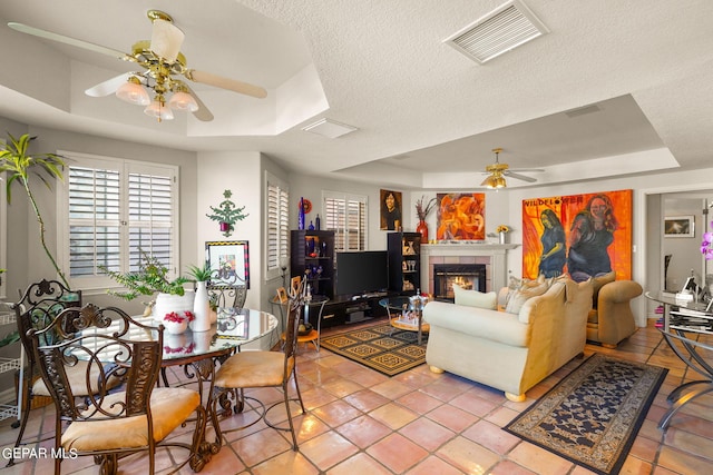 tiled living room featuring ceiling fan, a raised ceiling, and a textured ceiling