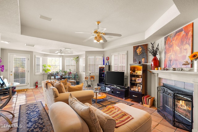 living room featuring a textured ceiling, a tray ceiling, and ceiling fan