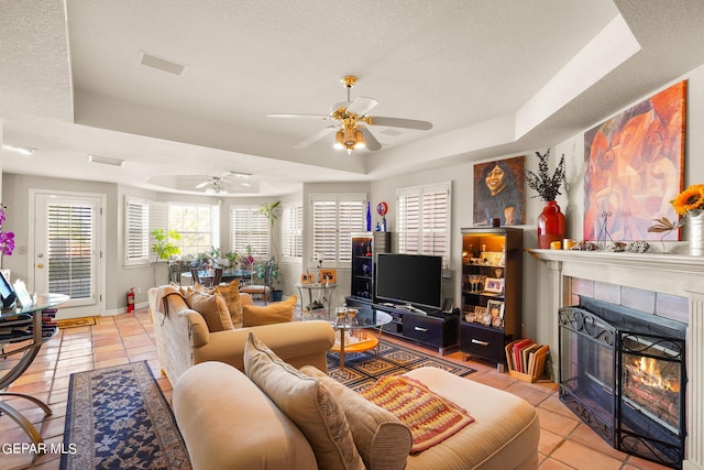 851 Via Alegre Ln, El Paso, TX 79912 - living area featuring a raised ceiling, a ceiling fan, a textured ceiling, a fireplace, and light tile patterned floors