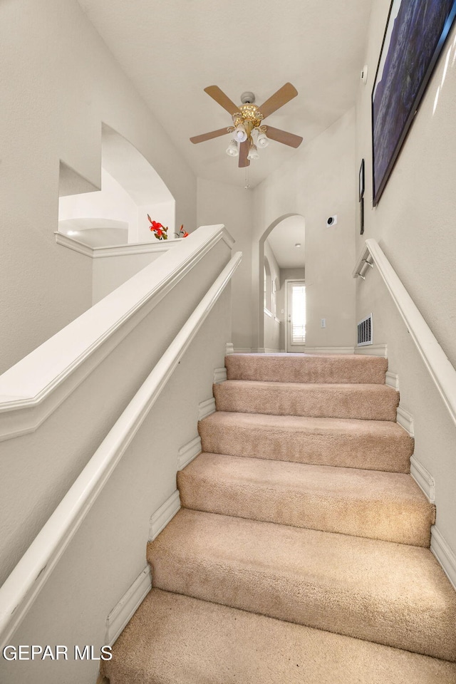 stairs featuring ceiling fan