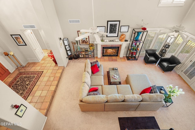 tiled living room featuring a tile fireplace, a high ceiling, and ceiling fan