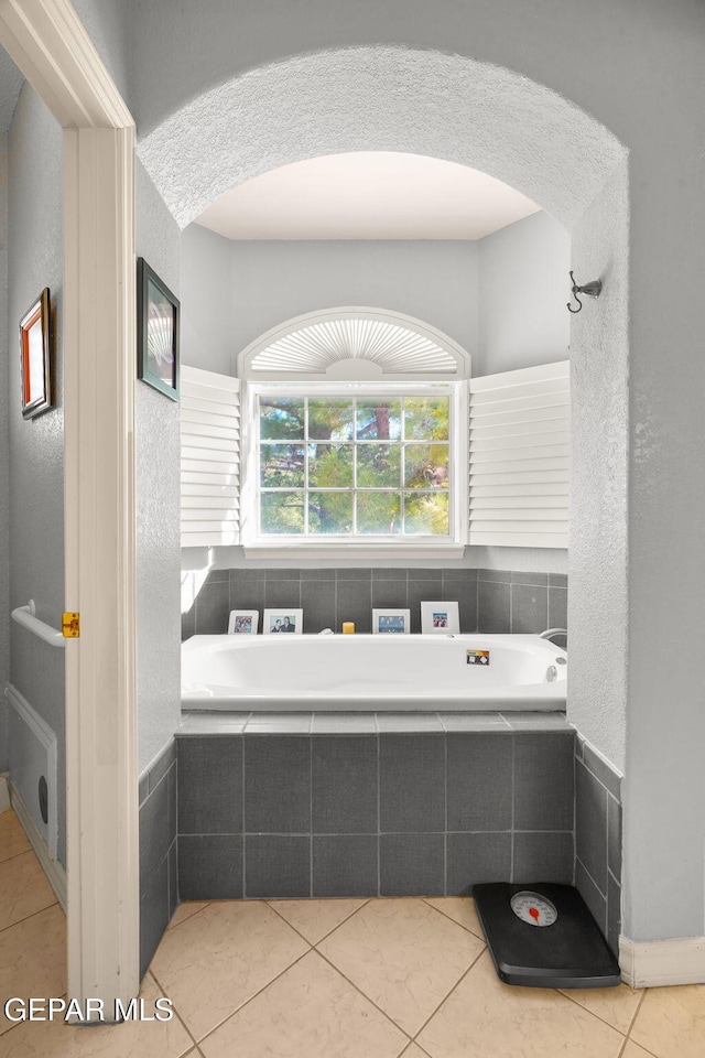 bathroom featuring tile patterned flooring and a relaxing tiled tub