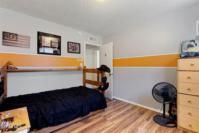 bedroom featuring a textured ceiling and light hardwood / wood-style flooring