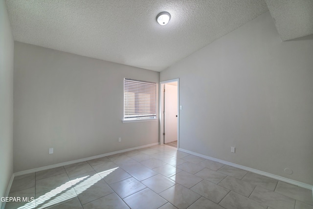 unfurnished room with a textured ceiling, lofted ceiling, and light tile patterned floors