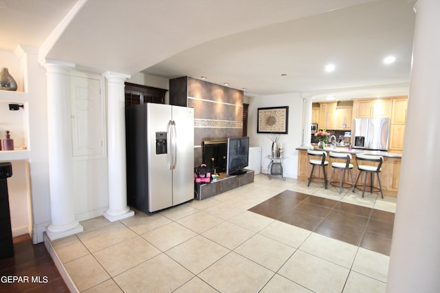 kitchen with light brown cabinetry, sink, light tile patterned floors, and stainless steel fridge