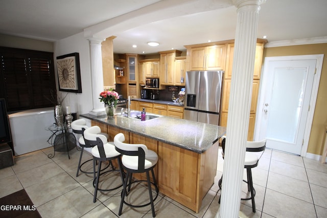 kitchen with sink, decorative columns, kitchen peninsula, appliances with stainless steel finishes, and dark stone countertops