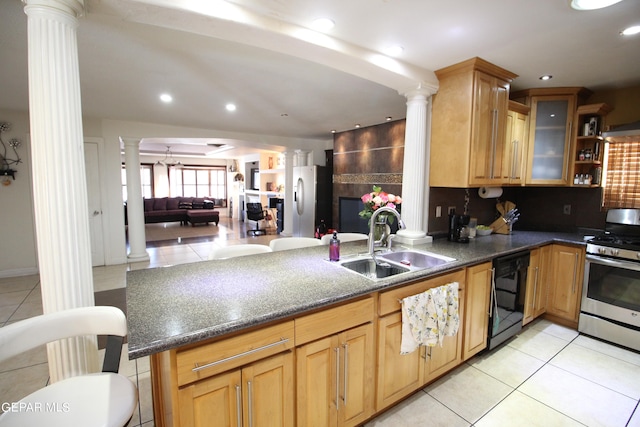 kitchen with sink, kitchen peninsula, stainless steel range with gas stovetop, decorative columns, and black dishwasher