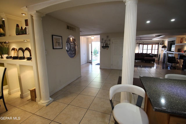 corridor with decorative columns and light tile patterned floors