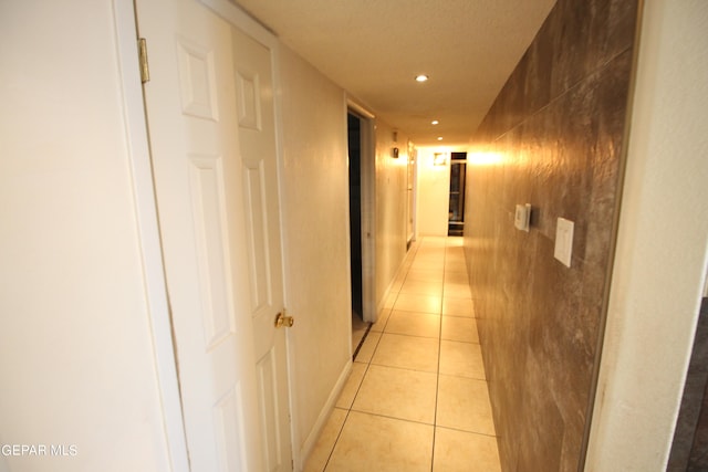 hallway featuring a textured ceiling and light tile patterned floors