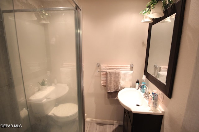 bathroom with wood-type flooring, an enclosed shower, vanity, and toilet