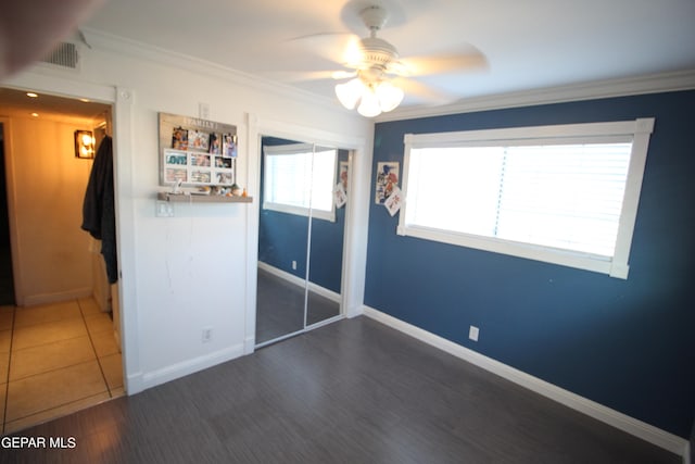 unfurnished bedroom with ornamental molding, a closet, ceiling fan, and dark tile patterned floors