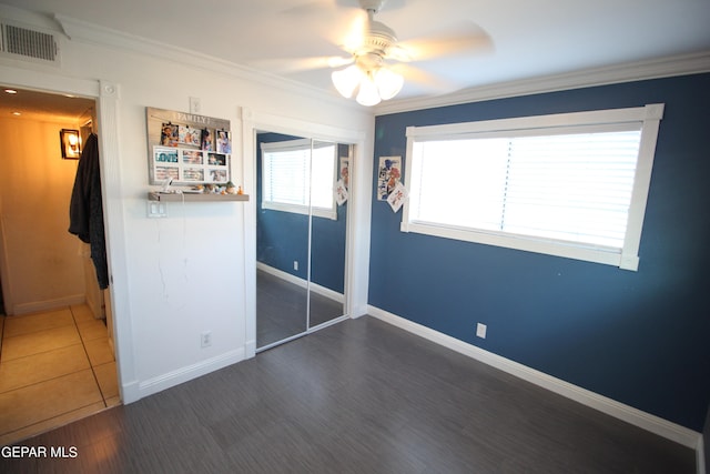 unfurnished bedroom featuring ornamental molding, dark wood-type flooring, ceiling fan, and a closet