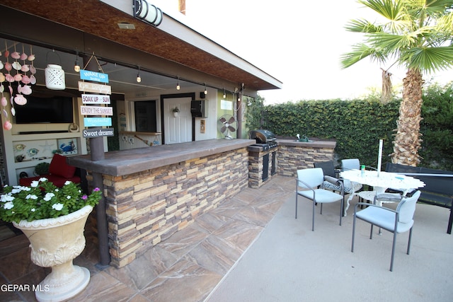 view of patio featuring exterior kitchen and a grill