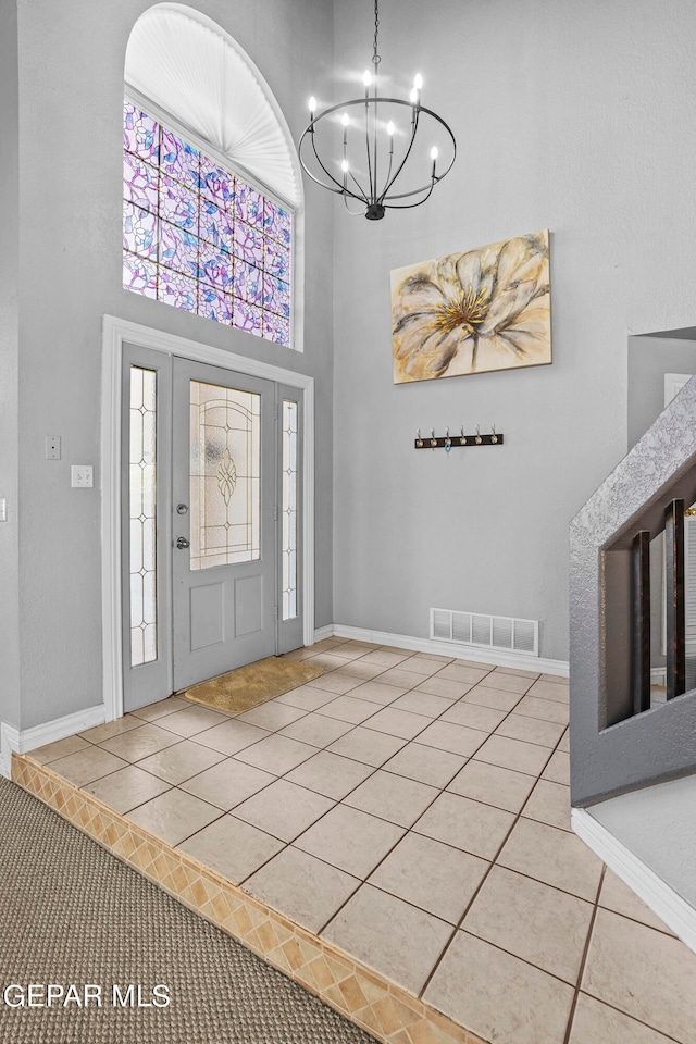 tiled foyer with a high ceiling, a healthy amount of sunlight, and a notable chandelier