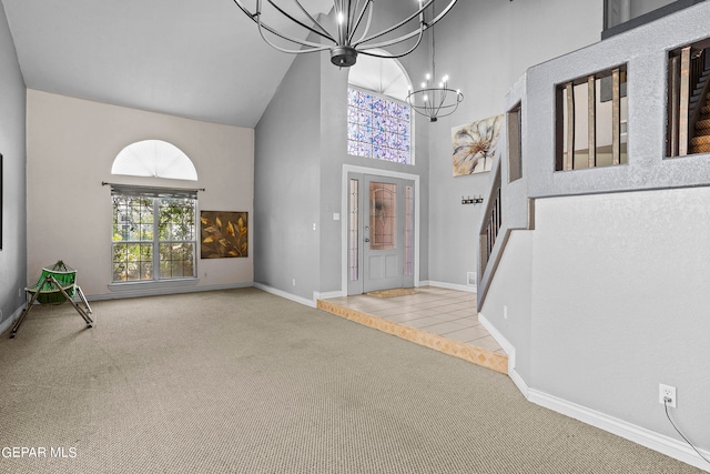 entryway with light carpet, high vaulted ceiling, and a chandelier