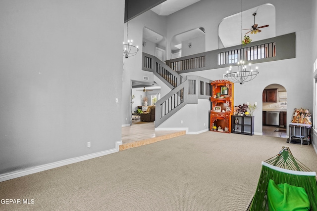 living room featuring ceiling fan with notable chandelier, a high ceiling, and light colored carpet