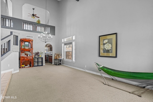 misc room with a high ceiling, carpet floors, and ceiling fan with notable chandelier