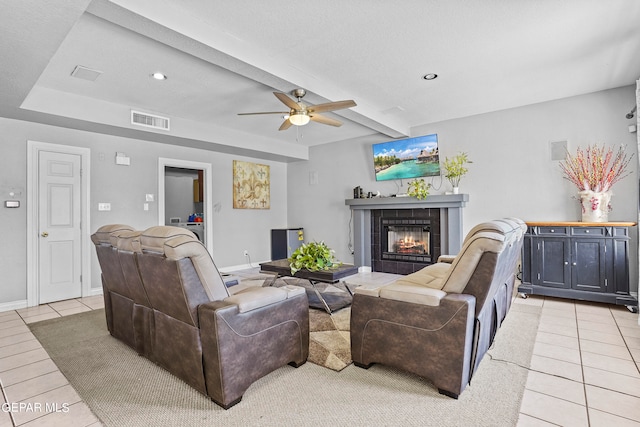 tiled living room featuring ceiling fan, a textured ceiling, beam ceiling, and a tile fireplace