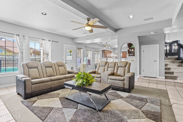 tiled living room featuring ceiling fan, beamed ceiling, plenty of natural light, and a textured ceiling