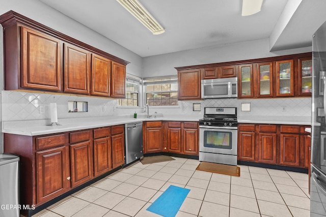 kitchen with stainless steel appliances, tasteful backsplash, sink, and light tile patterned floors