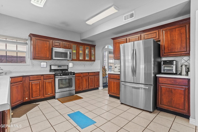 kitchen featuring stainless steel appliances, plenty of natural light, backsplash, and light tile patterned floors