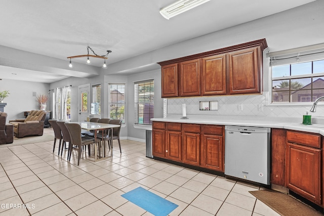 kitchen featuring light tile patterned flooring, plenty of natural light, stainless steel dishwasher, and tasteful backsplash