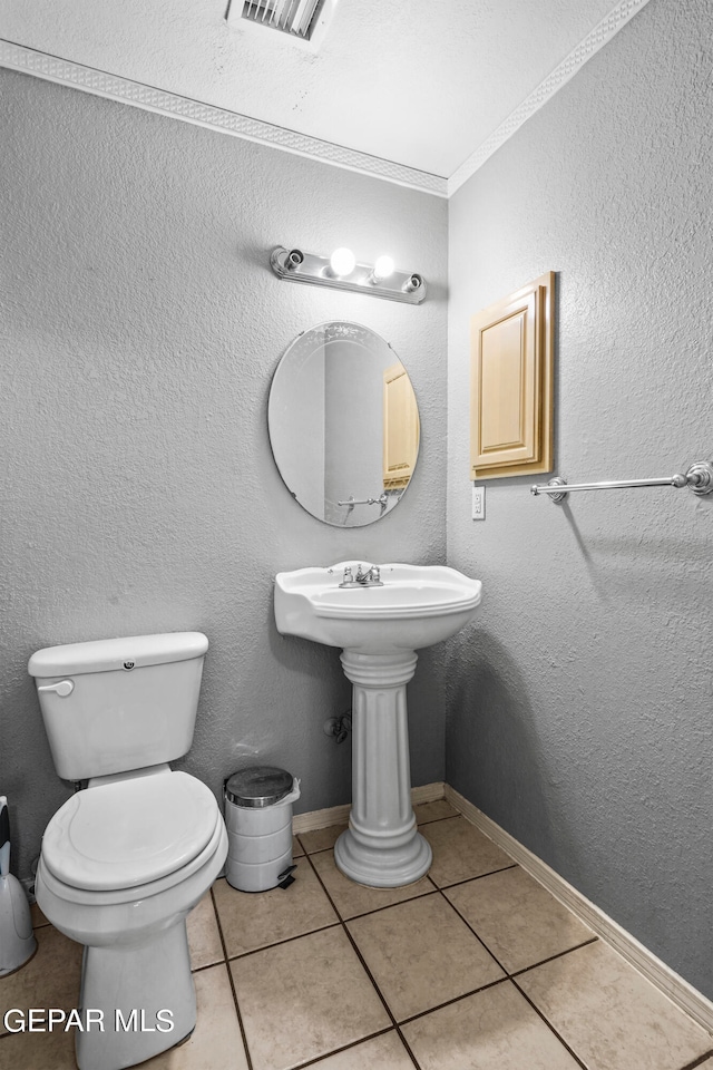 bathroom featuring tile patterned flooring, ornamental molding, and toilet